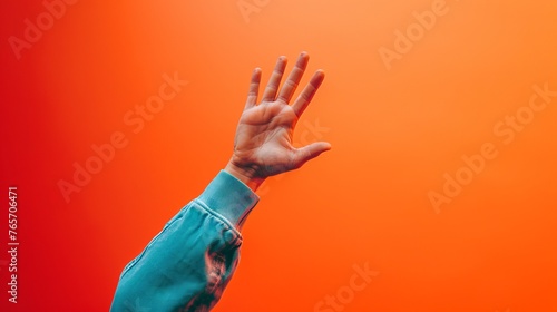 Vibrant Goodbye - A Close-Up of a Person’s Hand Waving Farewell Against a Warm, Orange Background photo