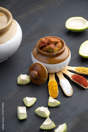 Homemade Mango Pickle or aam ka achar Kairi Loncha stored or preserved in China clay pot with Ingredients.