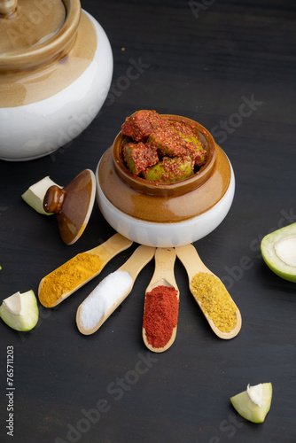 Homemade Mango Pickle or aam ka achar Kairi Loncha stored or preserved in China clay pot with Ingredients.