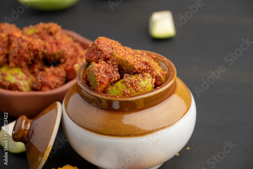 Homemade Mango Pickle or aam ka achar Kairi Loncha stored or preserved in China clay pot with Ingredients.