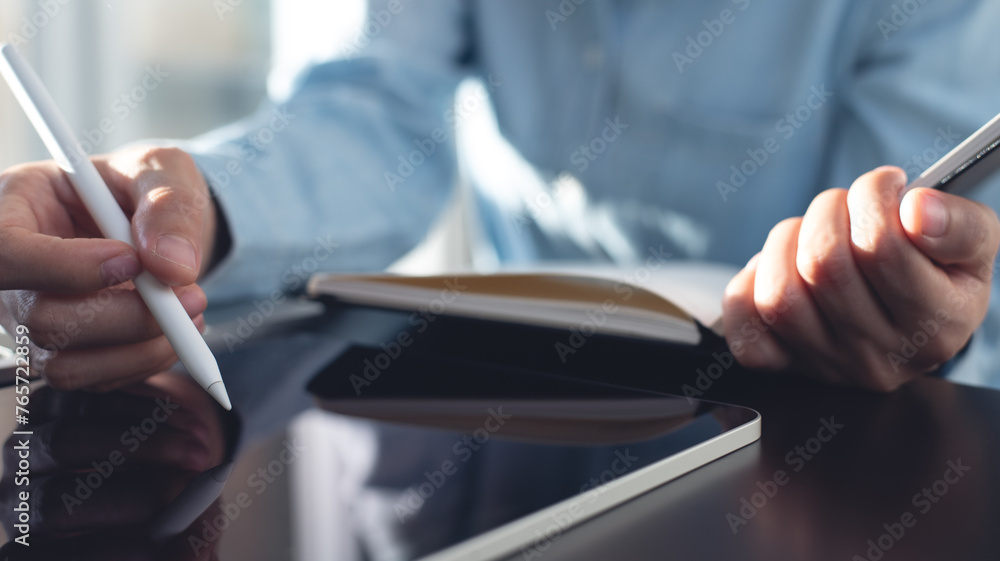 Business woman using stylus pen on digital tablet and planning business event on office table. Student studying online class and taking note on notebook, e-learning, business event planning, close up Business woman using stylus pen on digital tablet and planning business event on office table. Student studying online class and taking note on notebook, e-learning, business event planning, close up