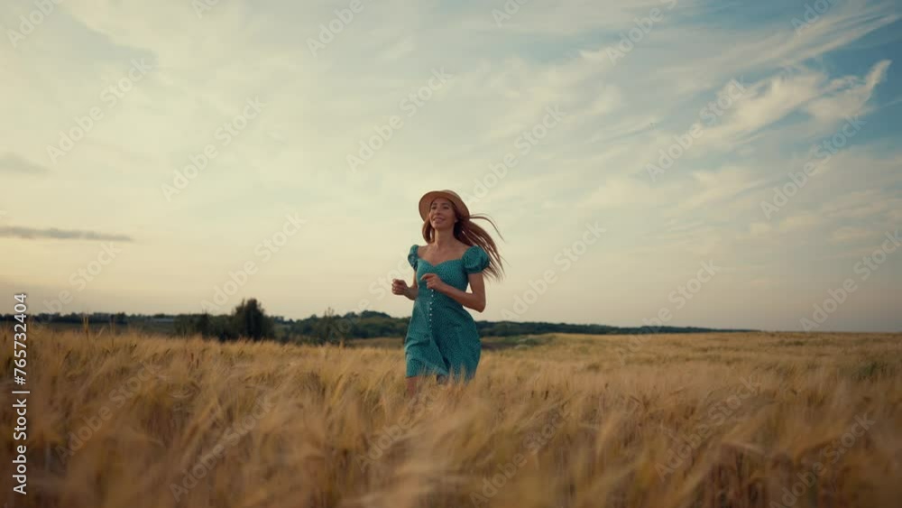 Carefree happy joyful woman in straw hat, dress running on wheat field at cloudy summer day feeling freedom, harmony, lightness and serenity. Smiling adult female enjoying nature living on farm. Carefree happy joyful woman in straw hat, dress running on wheat field at cloudy summer day feeling freedom, harmony, lightness and serenity. Smiling adult female enjoying nature living on farm.