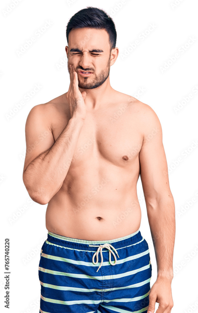 Young handsome man wearing swimwear touching mouth with hand with painful expression because of toothache or dental illness on teeth. dentist Young handsome man wearing swimwear touching mouth with hand with painful expression because of toothache or dental illness on teeth. dentist