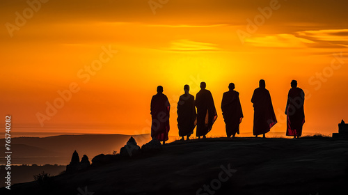 A group of monks are walking together in the sunset. Concept of peace and serenity as the monks make their way down the hill