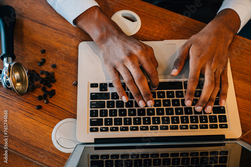 In the modern roastery office a multitasking business owner also a barista checks bean quality on laptop and machinery. Quality check assures premium coffee beans. Precision is the norm. photo