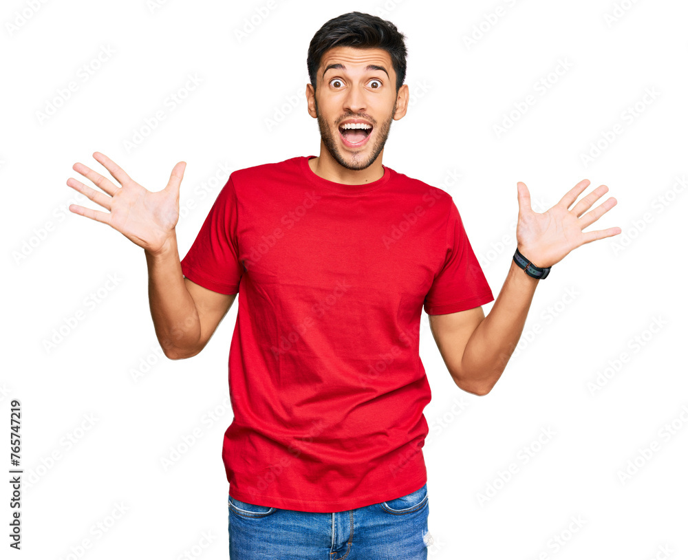 Young handsome man wearing casual red tshirt celebrating crazy and amazed for success with arms raised and open eyes screaming excited. winner concept Young handsome man wearing casual red tshirt celebrating crazy and amazed for success with arms raised and open eyes screaming excited. winner concept