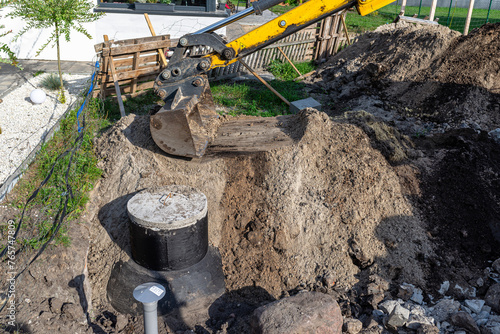 Using an excavator to bury a 10 m3 concrete septic tank located in the garden next to the house. photo