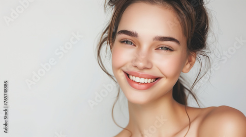 Portrait of a smiling woman with healthy skin and natural makeup on a studio background with copy space 