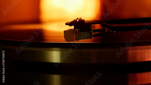 Headshell with the needle of the record player slowly lowers onto the vinyl record. photo