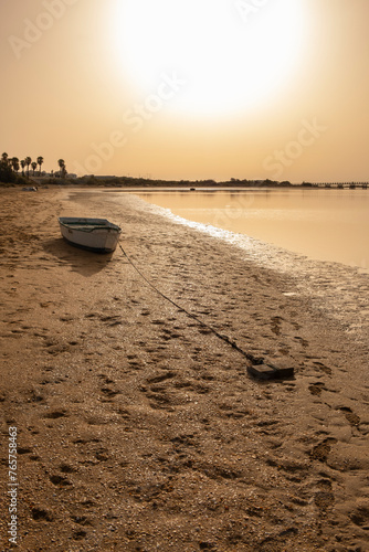 An old fishing boat rests stranded at low tide on a beach in the province of Huelva, Spain, at dawn