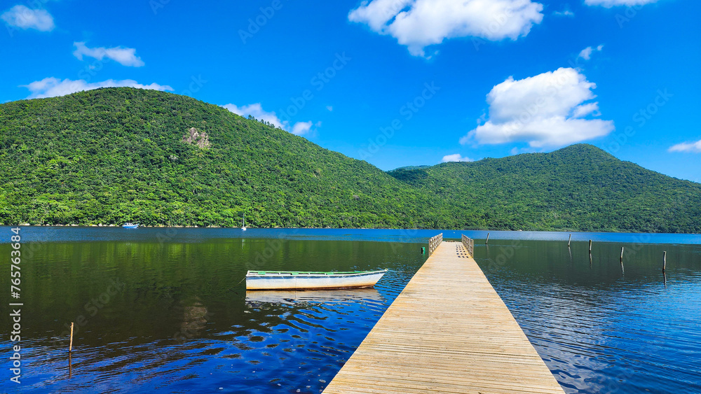 A Lone Boat on the Calm and Crystal-Clear Lake Waters under a Blue Sky with Scattered Clouds