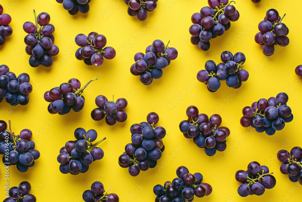 Ripe purple grapes on a bright yellow background, arranged neatly in a flat lay top view Ripe purple grapes on a bright yellow background, arranged neatly in a flat lay top view