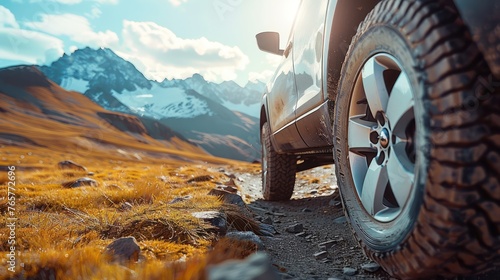 Travel concept with big 4x4 car against sunset and mountains. Closeup photo of offroad wheel © Koihime