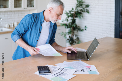 Senior man paying medical insurance bills on laptop at home