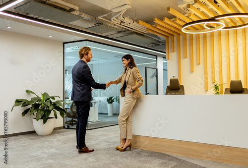 Warm Handshake Between Colleagues In Modern Office Lobby Under Ambient Lighting