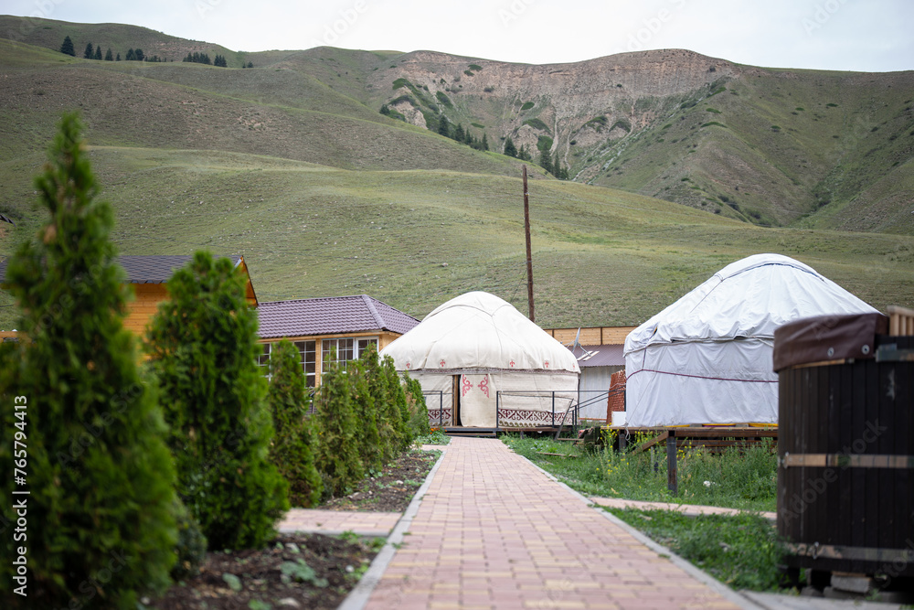 White yurt with red and brown traditional patterns on a green hill
