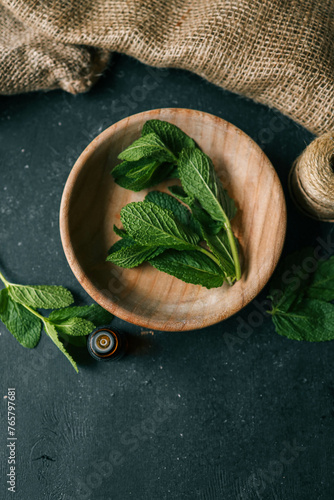 Bottle of essential oil with mint on wooden background
