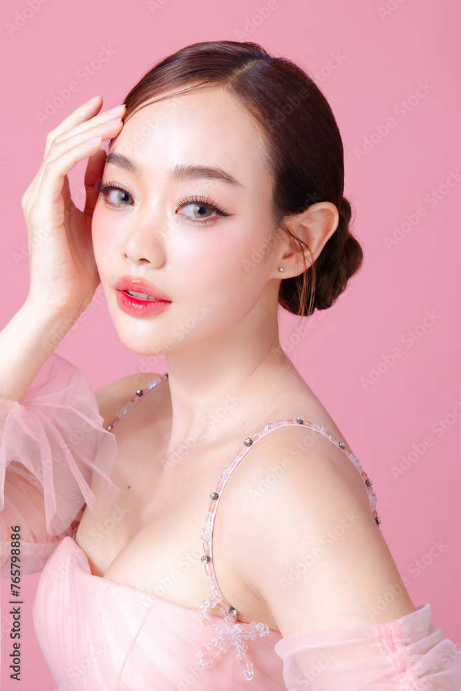 Beautiful young Asian woman model bun hair with natural makeup on face clean fresh skin on isolated pink background. Cute girl portrait, Facial treatment, Valentine concept.