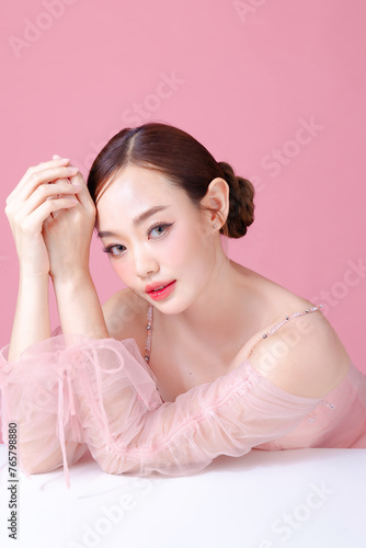 Beautiful young Asian woman model bun hair with natural makeup on face clean fresh skin on isolated pink background. Cute girl portrait, Facial treatment, Valentine concept.