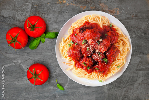 Homemade spaghetti and meatballs with tomato sauce. Top view table scene on a dark stone background.