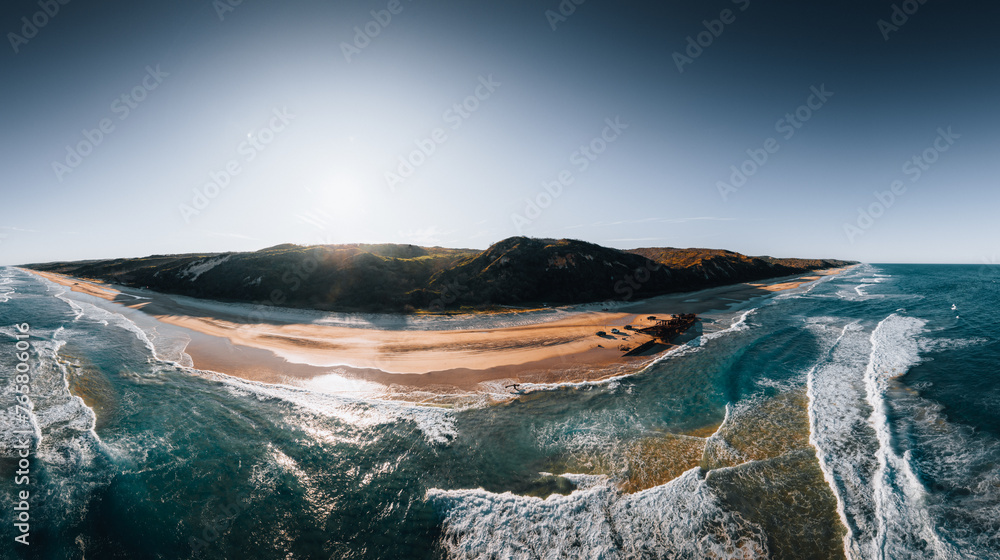 Obraz premium K'gari High angle aerial bird's eye drone view of the Maheno shipwreck on Seventy-Five Mile Beach on Fraser Island, Queensland, Australia. Beautiful sunset light with waves.
