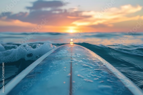 Surfboard on calm sea at sunset, tranquil moments before riding waves.