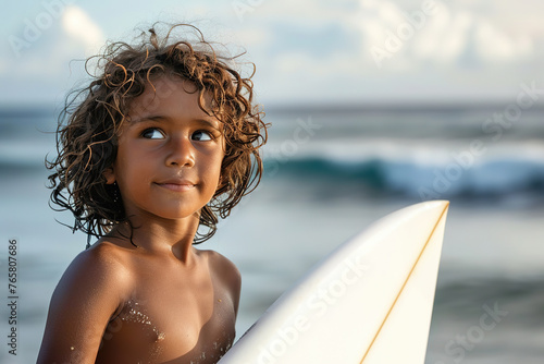 Young surfer with board on beach at sunset.