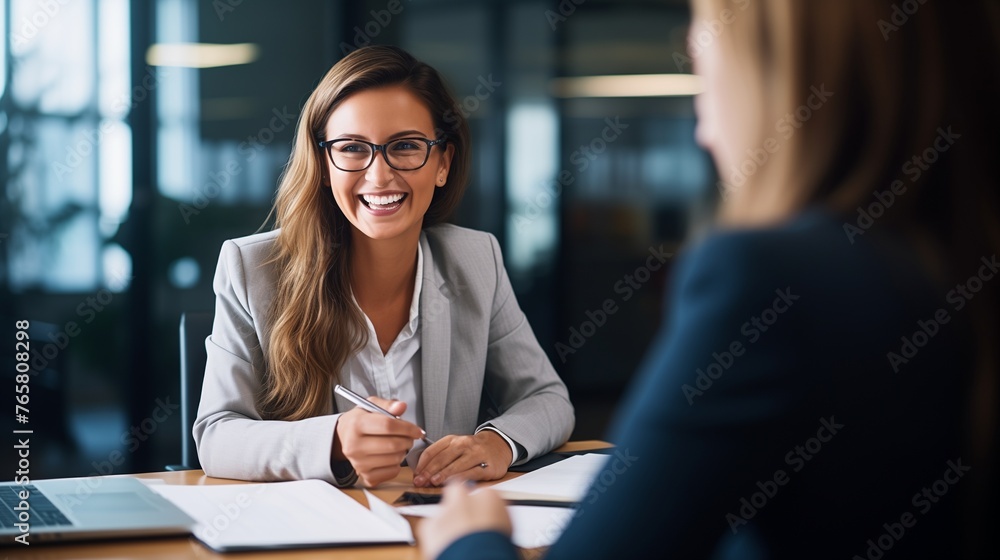 This image captures a professional scene in an office where a smiling female financial advisor, attorney, or bank manager is engaged in a business meeting with a client. This image captures a professional scene in an office where a smiling female financial advisor, attorney, or bank manager is engaged in a business meeting with a client.
