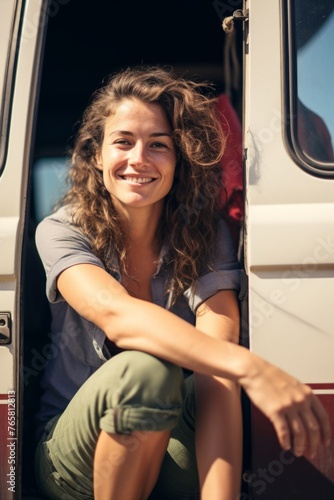 A happy girl sits in the doorway of a motorhome on a sunny beautiful day. Generative AI.