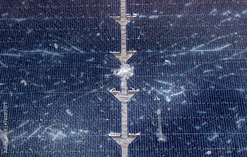 Close up view of damaged broken solar panel tempered glass cell. Stone dent in the middle with spiderweb cracks around.