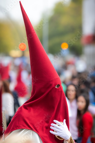 Nazareno, bearer in a procession of the easter week in Seville, andalusia, Spain. 2024 Semana Santa. Red hood, procession of 23.03.2024