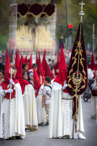 Nazareno, bearer in a procession of the easter week in Seville, andalusia, Spain. 2024 Semana Santa. Red hood, procession of 23.03.2024