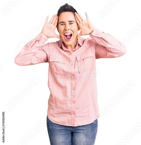 Young woman with short hair wearing casual clothes smiling cheerful playing peek a boo with hands showing face. surprised and exited