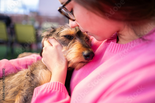 684 / 5.000Resultados de traducciónResultado de traducciónA young woman hugs her young purebred wire-haired dachshund with love and affection. She is in arms in a calm and relaxed situation photo