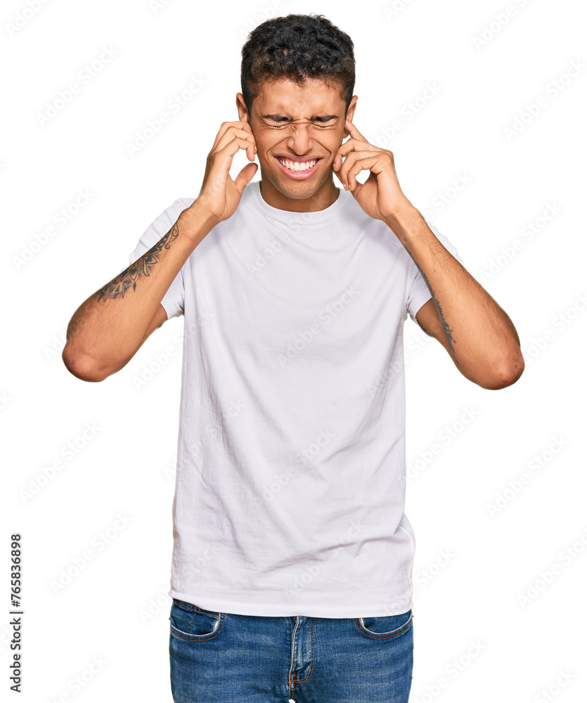 Young handsome african american man wearing casual white tshirt covering ears with fingers with annoyed expression for the noise of loud music. deaf concept. Young handsome african american man wearing casual white tshirt covering ears with fingers with annoyed expression for the noise of loud music. deaf concept.