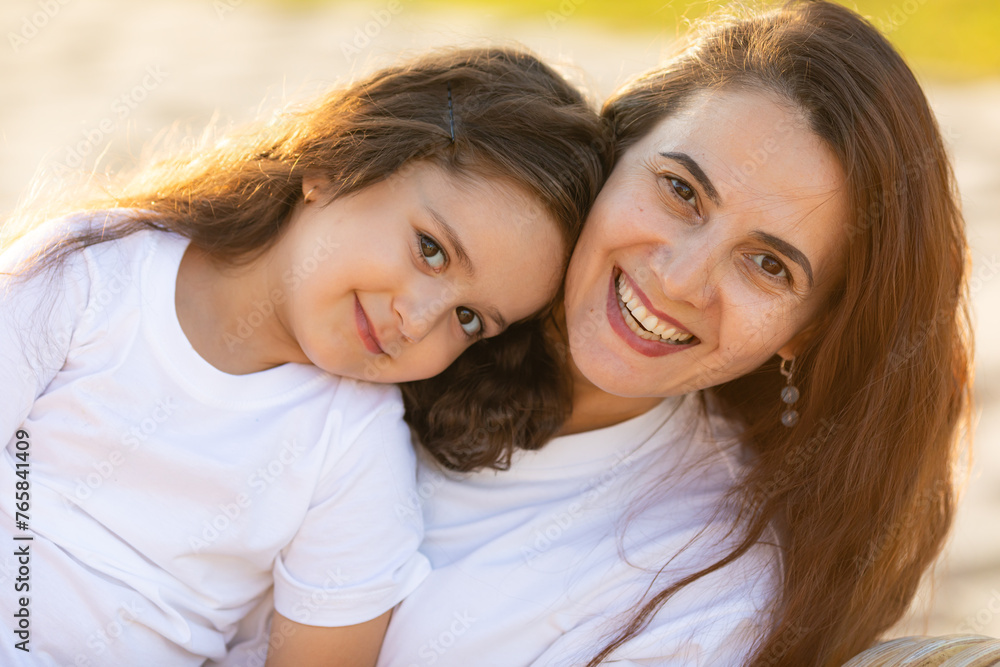 Happy mother having fun and hugging with her daughter outdoor - Family and love concept. Portrait of mother and daughter in the city park at summer sunset Happy mother having fun and hugging with her daughter outdoor - Family and love concept. Portrait of mother and daughter in the city park at summer sunset