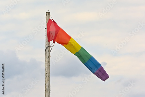 Wind flag with rainbow colors waving on a cloudy sky photo