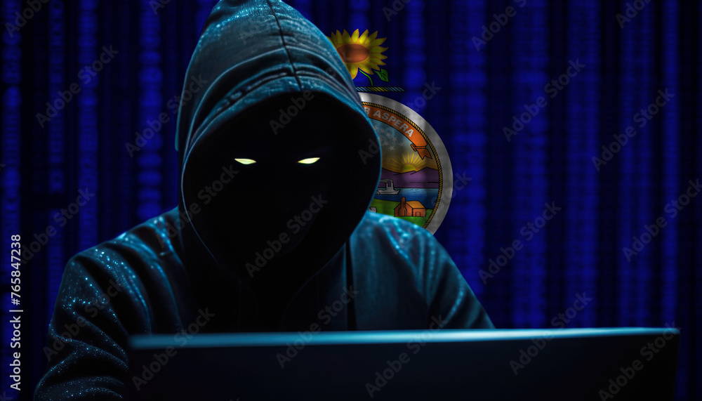Hacker in a dark hoodie sitting in front of a monitors with Kansas flag and background cyber security concept Hacker in a dark hoodie sitting in front of a monitors with Kansas flag and background cyber security concept