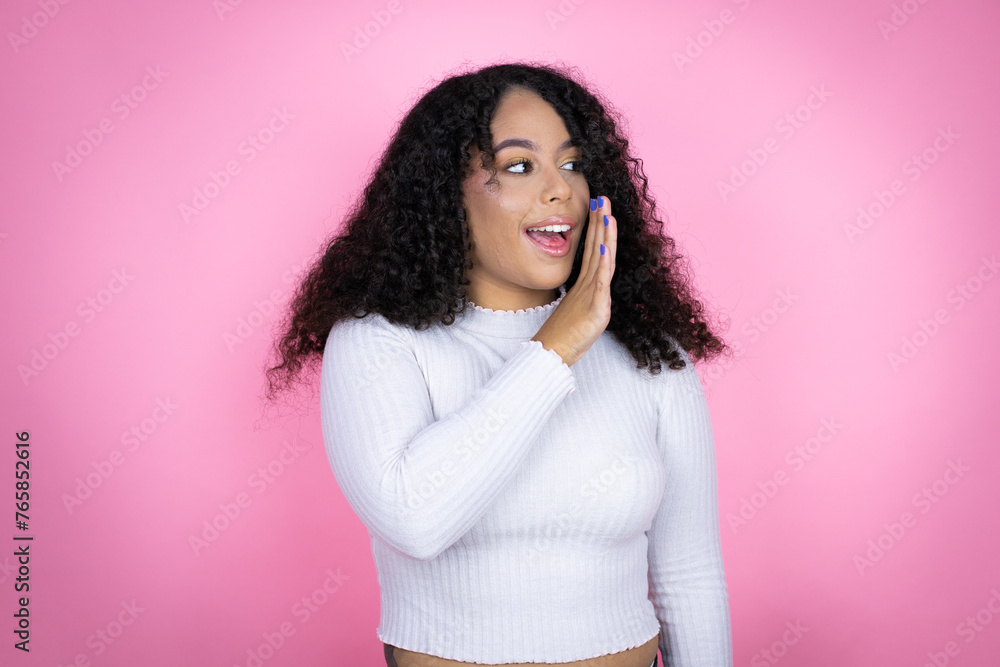 African american woman wearing casual sweater over pink background hand on mouth telling secret rumor, whispering malicious talk conversation African american woman wearing casual sweater over pink background hand on mouth telling secret rumor, whispering malicious talk conversation