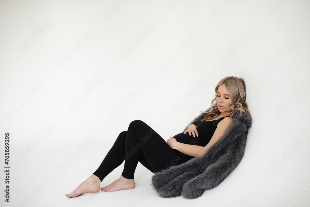 Pretty pregnant woman wearing stylish clothes over white background. Maternity.