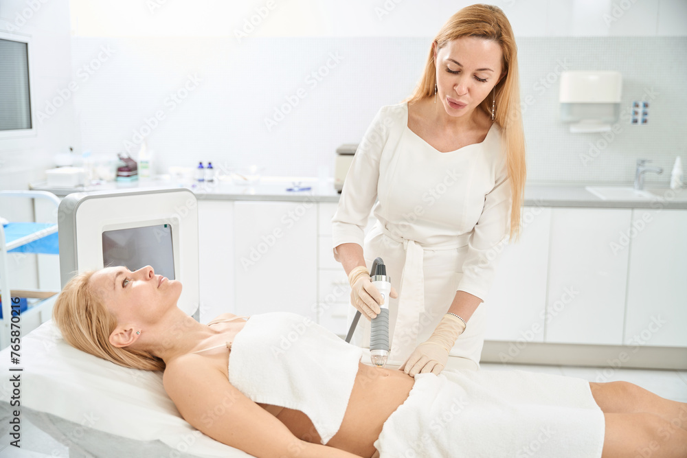 Cosmetologist carrying lifting procedure of female abdomen Cosmetologist carrying lifting procedure of female abdomen
