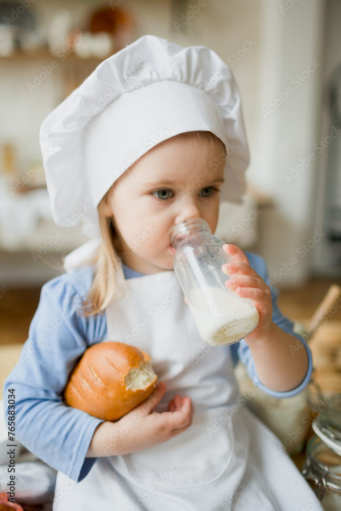 Girl cook 3 years old in a beautiful kitchen, in a chef's hat, in an apron, daylight Girl cook 3 years old in a beautiful kitchen, in a chef's hat, in an apron, daylight
