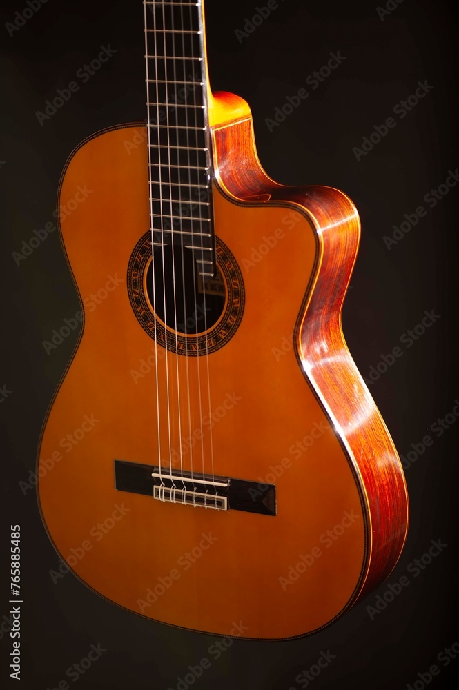 Obraz premium Classical Spanish flamenco guitar close up, dramatically lit isolated on black background with copy space.