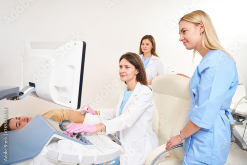 Gynecologist doing ultrasound scanning of woman pregnant belly near doctors