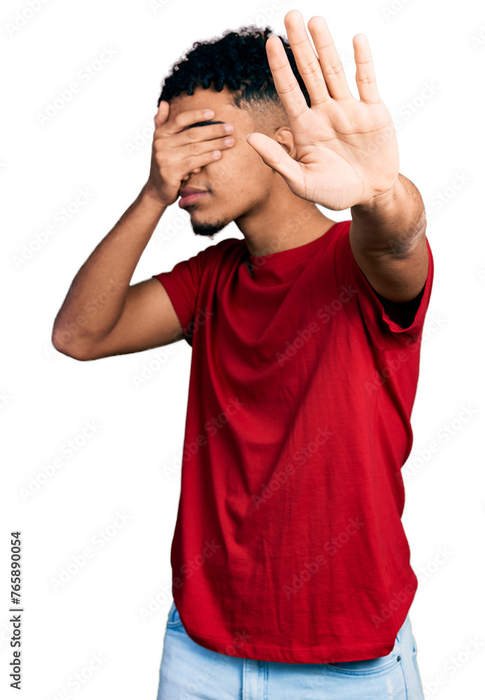 Young african american man wearing casual red t shirt covering eyes with hands and doing stop gesture with sad and fear expression. embarrassed and negative concept. Young african american man wearing casual red t shirt covering eyes with hands and doing stop gesture with sad and fear expression. embarrassed and negative concept.