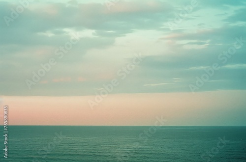 A large body of water sits still under a cloudy sky, creating a dramatic and moody atmosphere