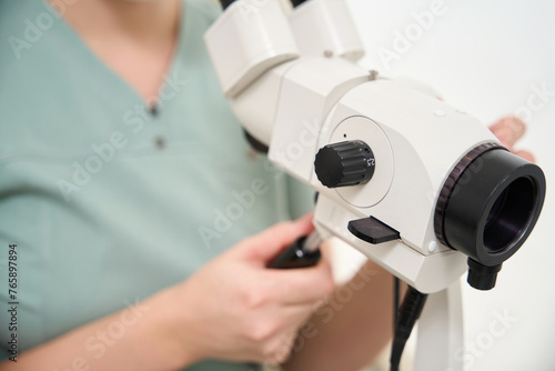 Focus of microscope in hands of blurred female doctor during work in clinic