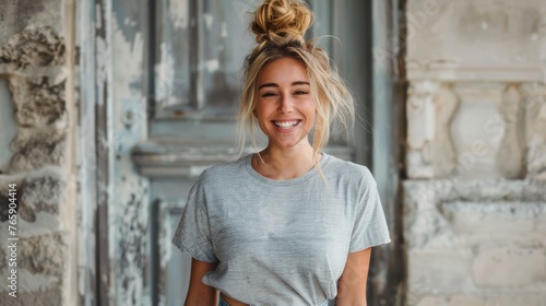 Smiling young woman in casual grey t-shirt with urban decay backdrop. Natural light portrait photography.