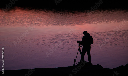 Fotografie Contraluz de un fotógrafo preparando su cámara