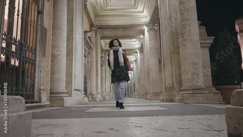 Stylish business woman walk on passage columns at Direzione museum at Capitoline in Rome, Italy at night, slow motion photo